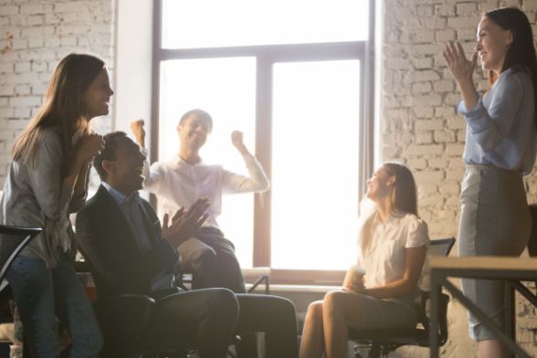 group of 5 people in an office meeting, showing excitement