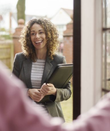 Woman standing in doorway, smiling, holding a tablet